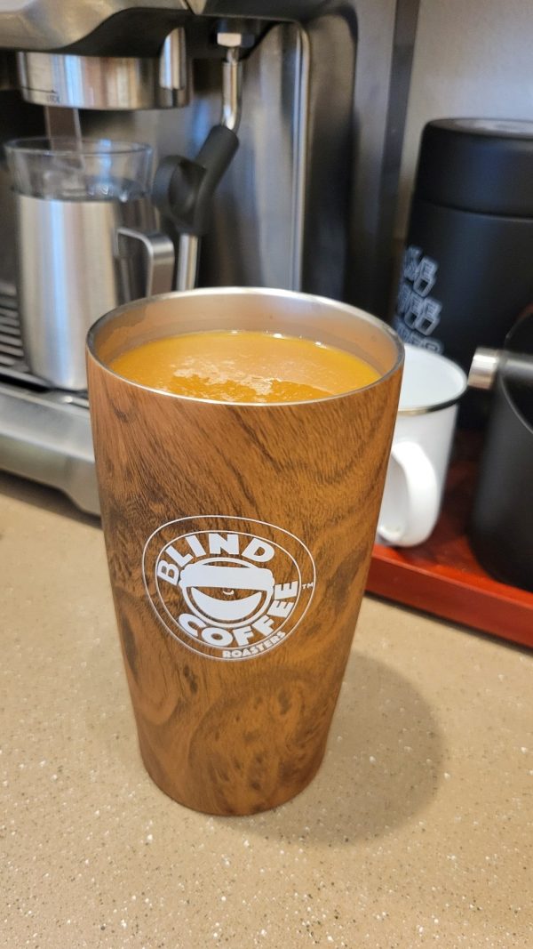 Photo of the stainless steel BCR Tumbler with woodtone color, white BCR logo holding coffee with cream