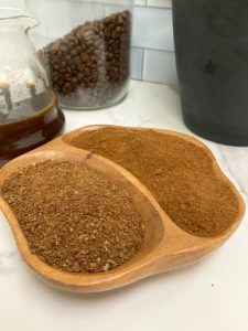 Close up of a divided bowl with coarse ground and fine ground coffee with pour over pitcher and coffee canister in the background.